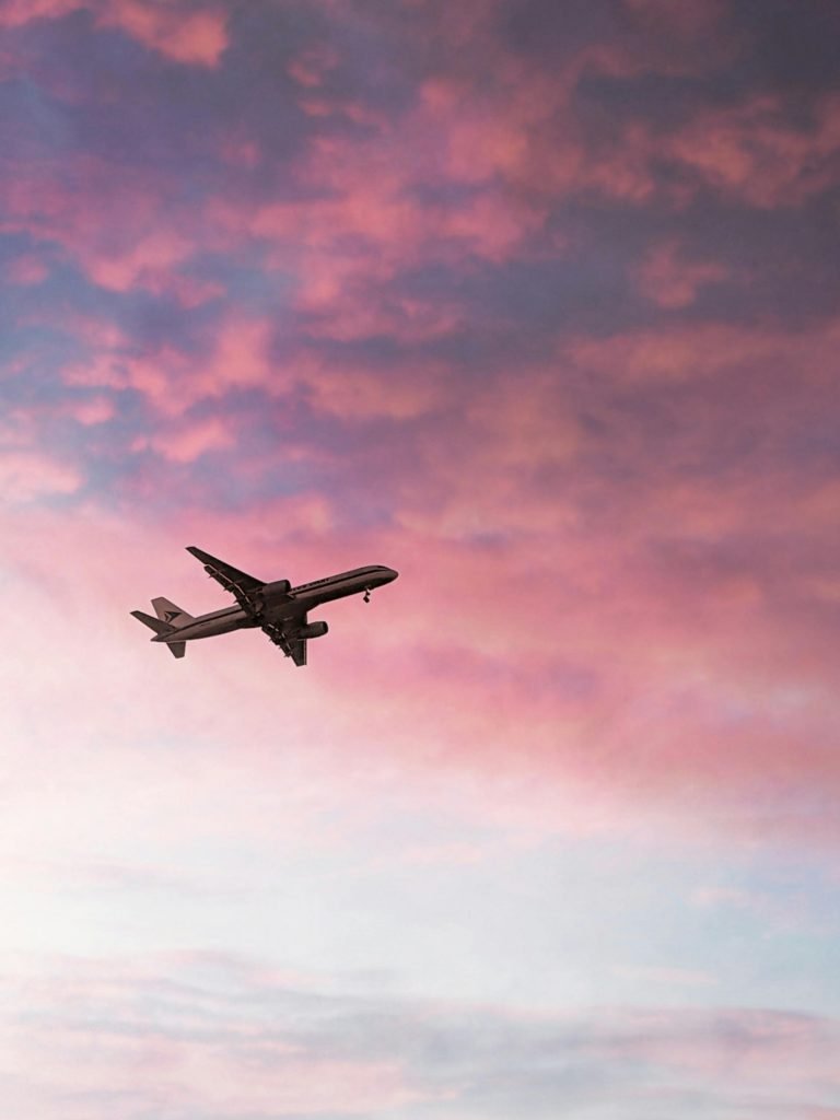 A stunning view of an airplane flying through colorful sunset skies, symbolizing travel and adventure.