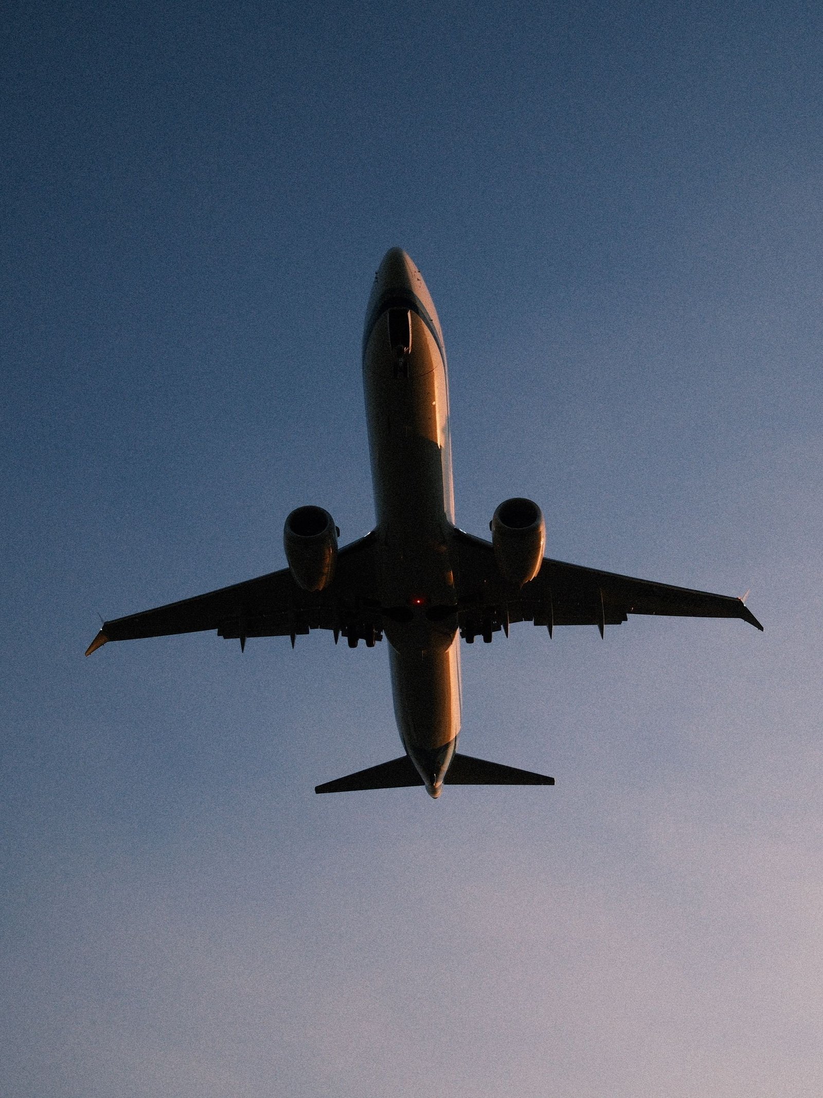 Low angle view of airplane silhouette against a twilight sky, showcasing flight dynamics.
